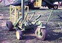 Having already steered and positioned the lift next to his combine, an adult male (now in the base frame seat) is preparing to power the lift up to the machine cab.