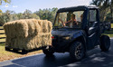 UTV with modular lift on front carrying a pallet with bales of hay